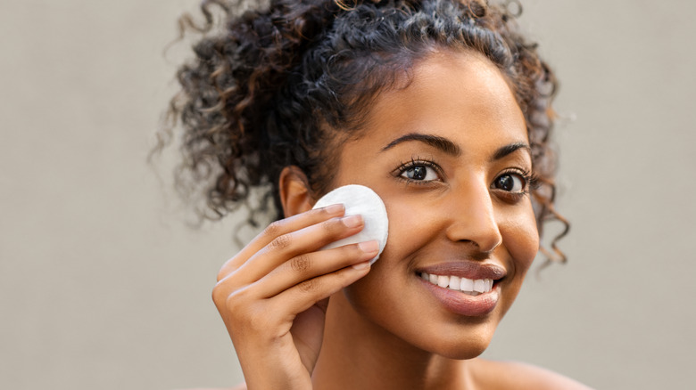 Woman using cotton pad on face 