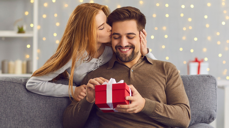 Girl kissing her boyfriend and giving him a present