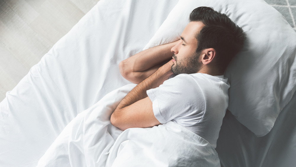 Man sleeping in a bed with off-white bedding