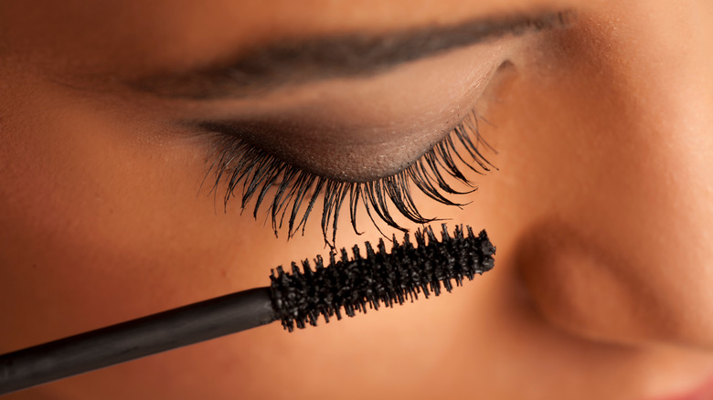 A woman putting mascara on