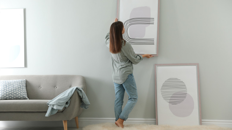 Woman hanging picture on wall