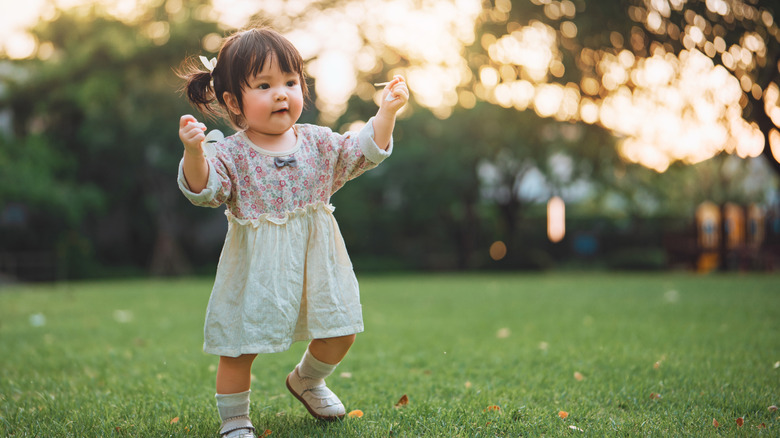 A baby girl walking on grass