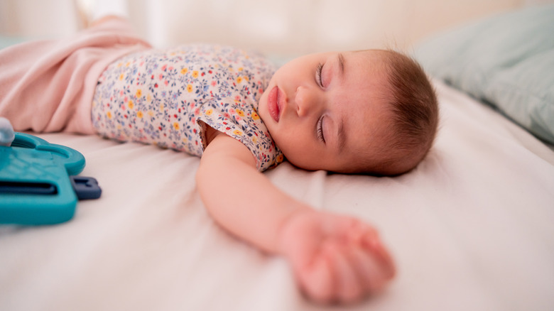 a baby girl sleeping with one arm up