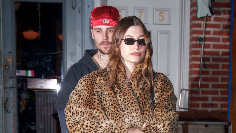 Justin Bieber stands behind Hailey Bieber