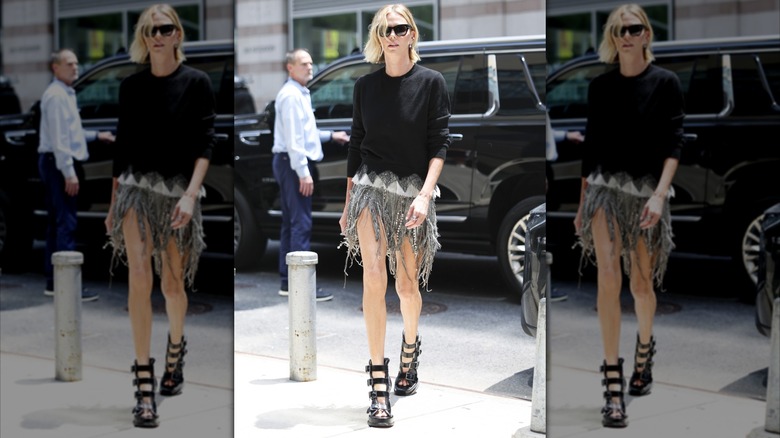 Charlize Theron in black sunglasses black sweater and short beaded and fringe skirt