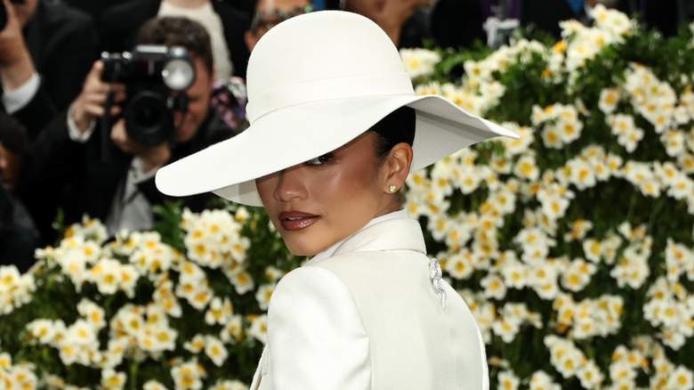 Zendaya wearing white big hat and looking over shoulder