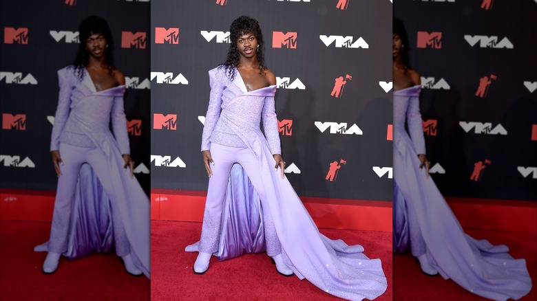 Lil Nas X in purple suit and skirt posing on VMAs red carpet