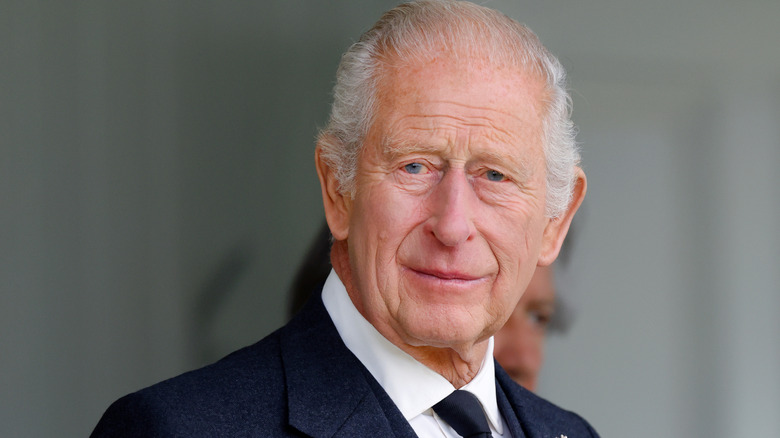 King Charles III smiling in a black suit