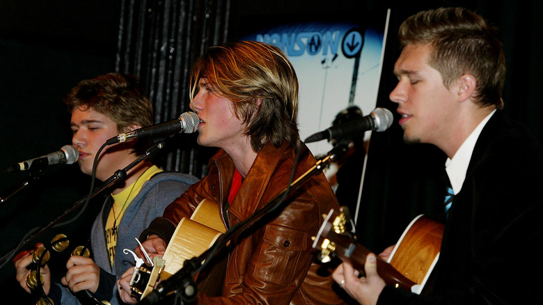 Hanson brother performing with mics and guitars 