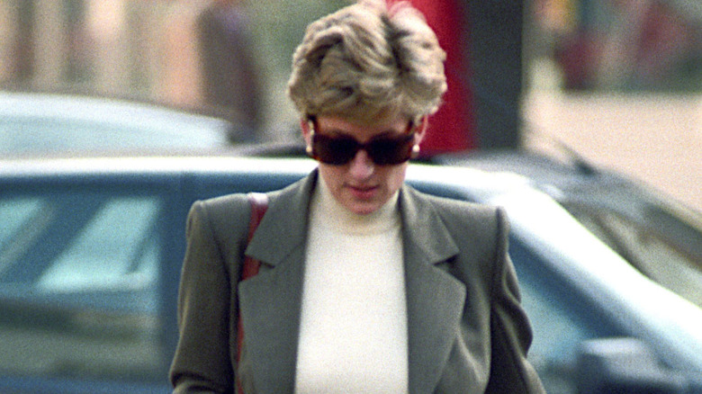 Princess Diana wearing sunglasses and walking with her head down