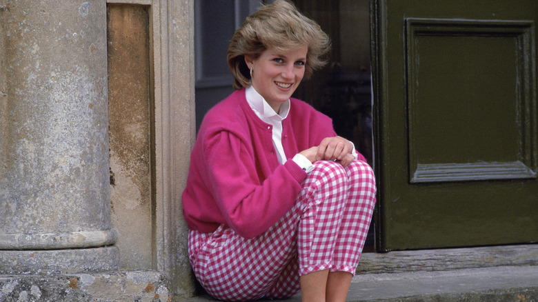 A smiling Princess Diana sitting on steps