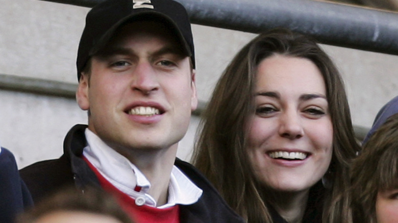 A young Prince William and Kate Middleton watch a sports match from a seated arena