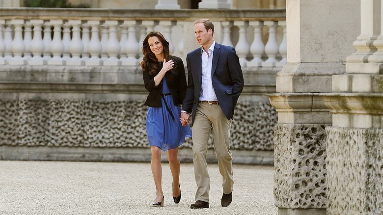 Kate Middleton and Prince William hold hands in an outdoor setting