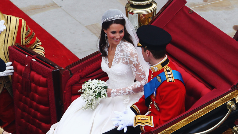 Kate Middleton holds her bridal bouquet while looking at Prince William in a carriage