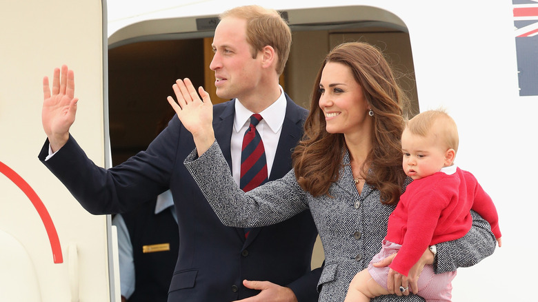 Prince William, Kate Middleton, and a baby Prince George stand outside a plane