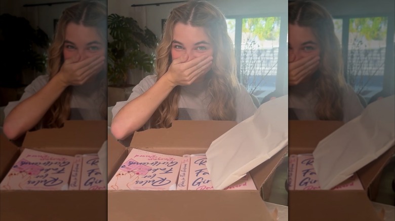 Raegan Revord opening a box of her novels