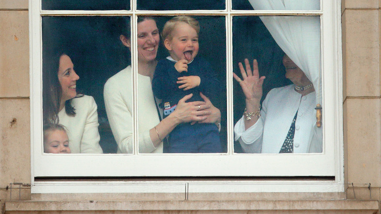 Maria Borrallo holding a laughing Prince George in a window