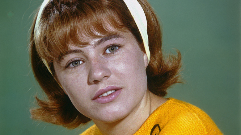 Patty Duke wearing a headband and yellow top