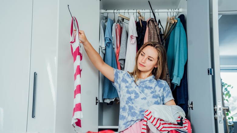 woman hanging clothes in closet