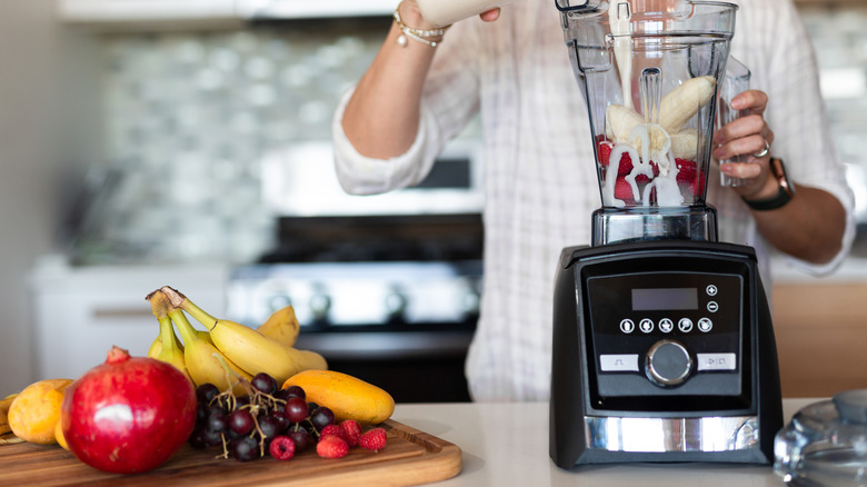 Woman preparing smoothie in a blender