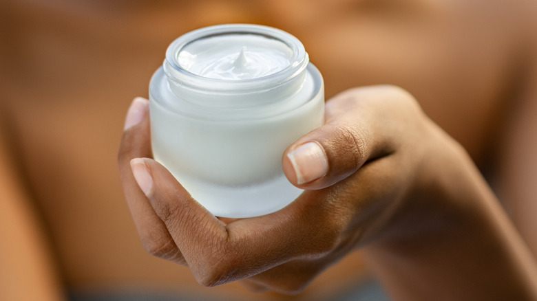 Woman holding a jar of face cream in her hands