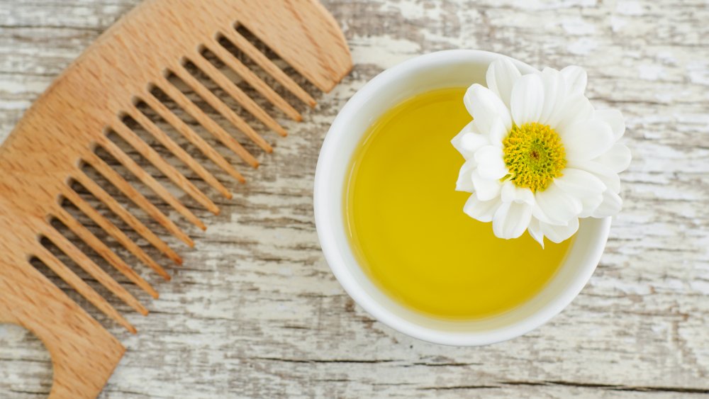 A tiny bowl of olive oil next to a wide-tooth comb 