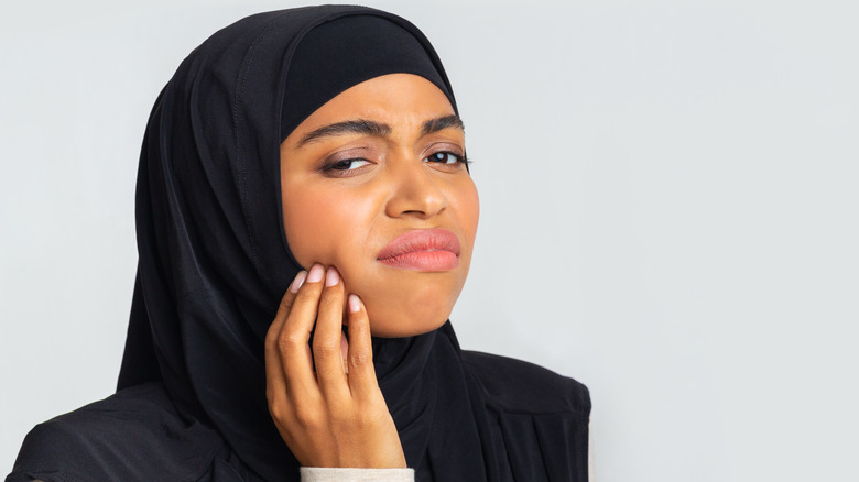 Woman touching her cheek, looking upset