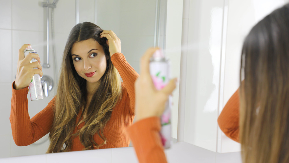 woman spraying dry shampoo into hair