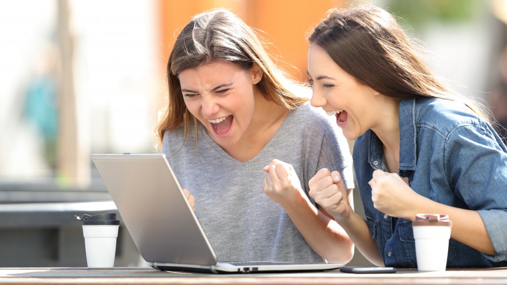 Two women excited by laptop outside