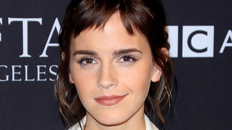 A close-up of Emma Watson with dark hair and bangs