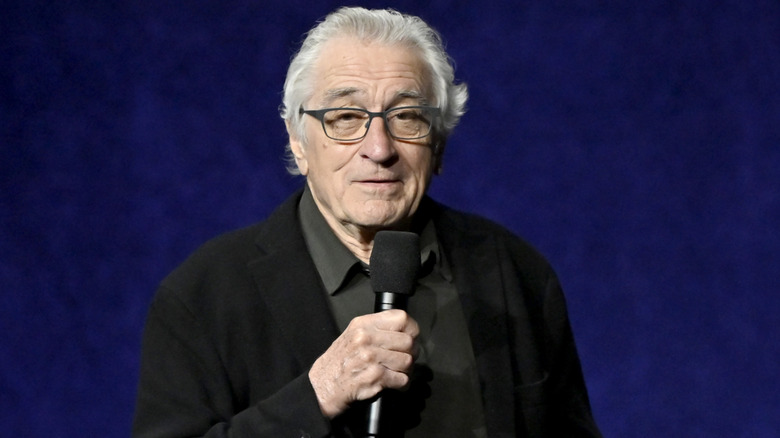 Robert De Niro holds a microphone onstage during CinemaCon 2026