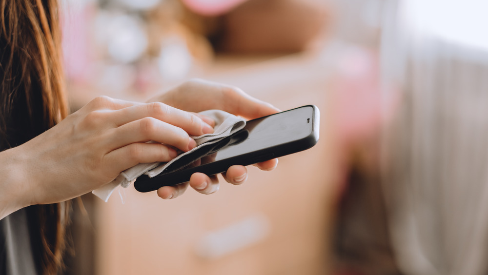 Woman disinfecting phone with cloth