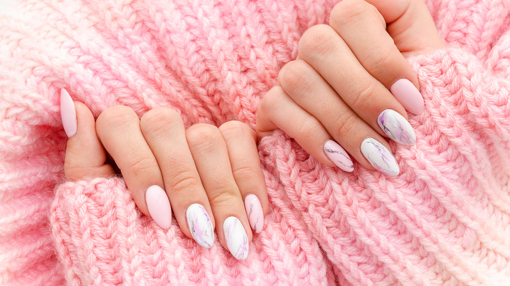 Closeup of manicured fingernails on woman in a pink sweater.