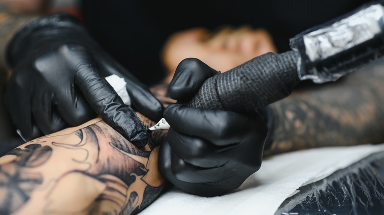 Person getting tattooed with black ink