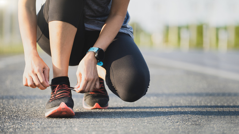 Woman ties her shoe while running