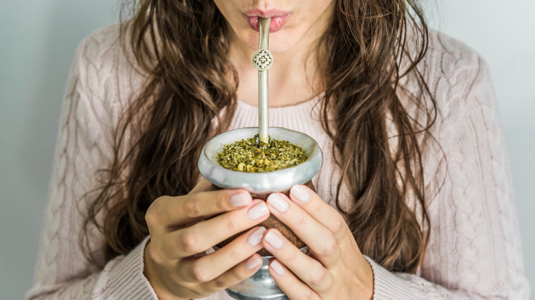 Woman drinking yerba mate out of a traditional gourd and metal straw