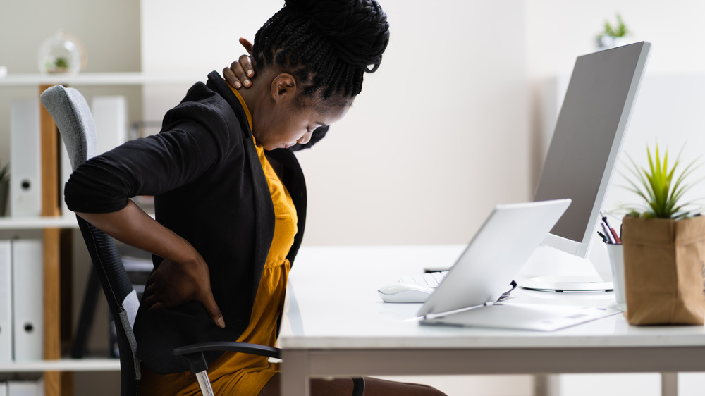 Woman sitting at a desk, experiencing neck and back pain 