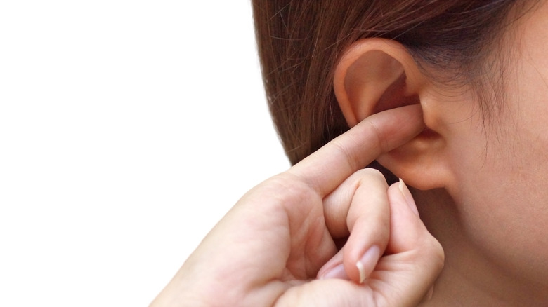 woman with pinky finger in her ear