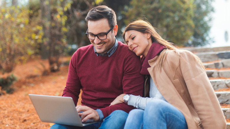 A couple on a computer in the park