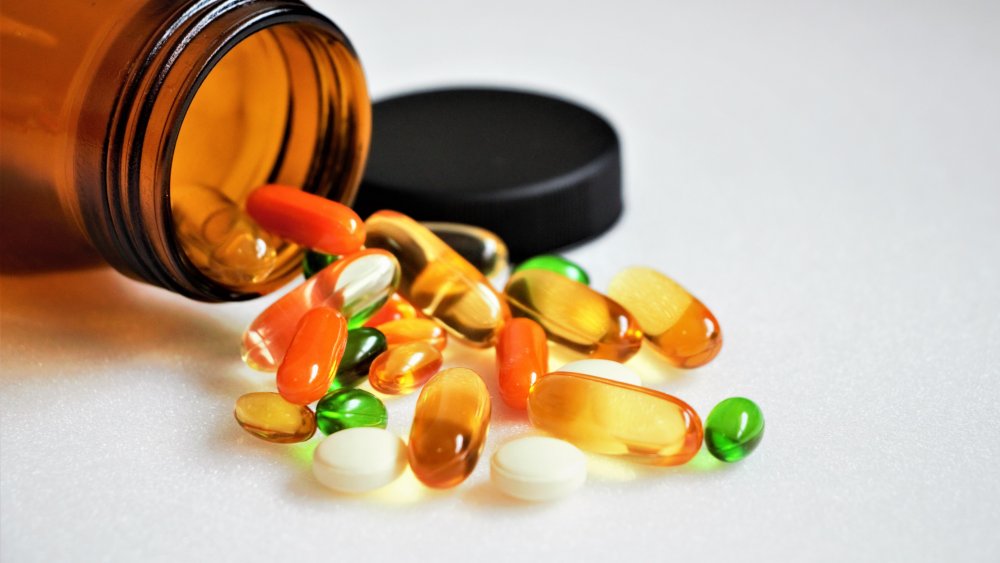 A bottle of vitamin capsules spilled onto a table 