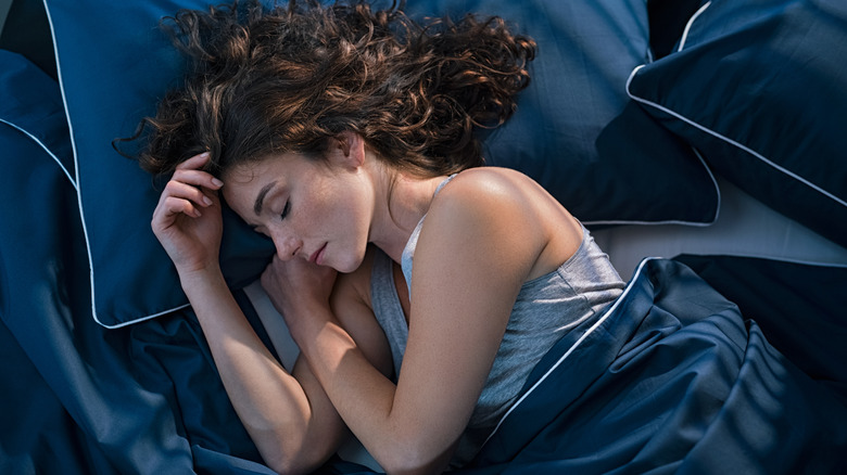 Woman sleeping on blue sheets
