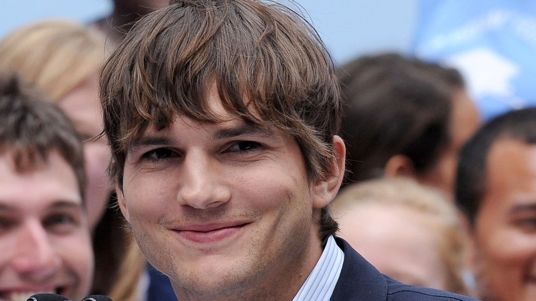 Ashton Kutcher smiles for the camera at an event.