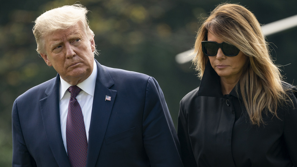 Donald Trump in blue suit with Melania Trump in dark sunglasses