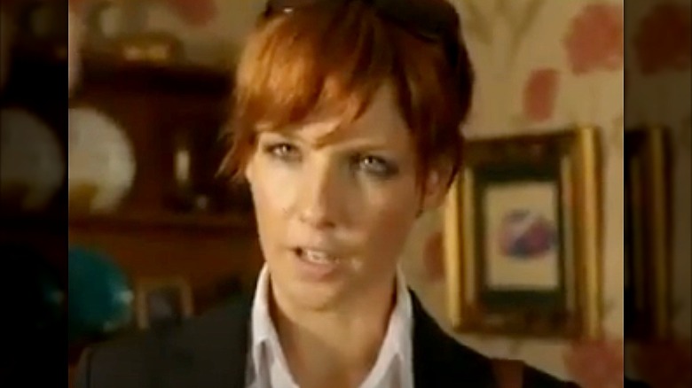 Kelly Reilly in white shirt and black jacket with hair up not smiling in Above Suspicion