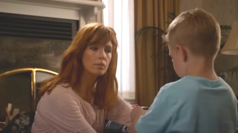 Kelly Reilly in white shirt with long hair in front of fireplace not smiling