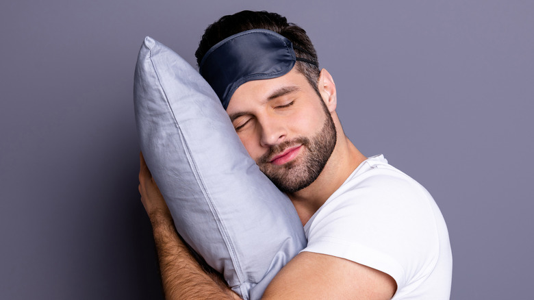 Man sleeping with purple pillow, eye mask