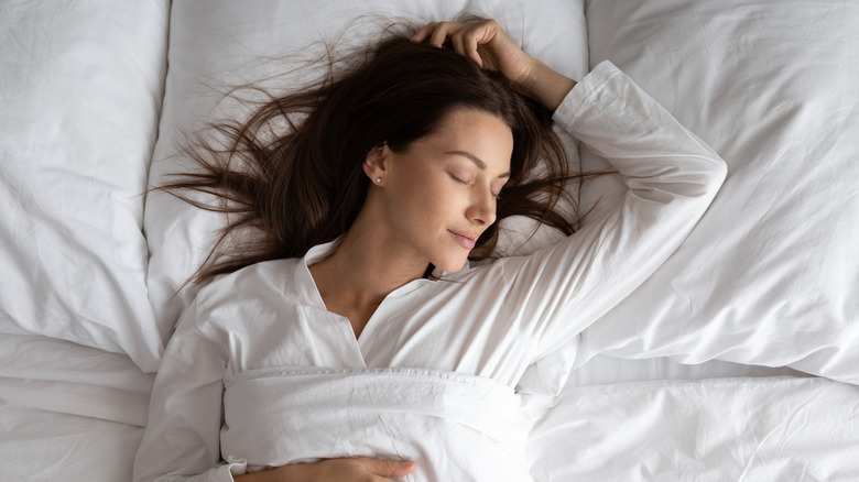 Woman asleep on white bedsheets