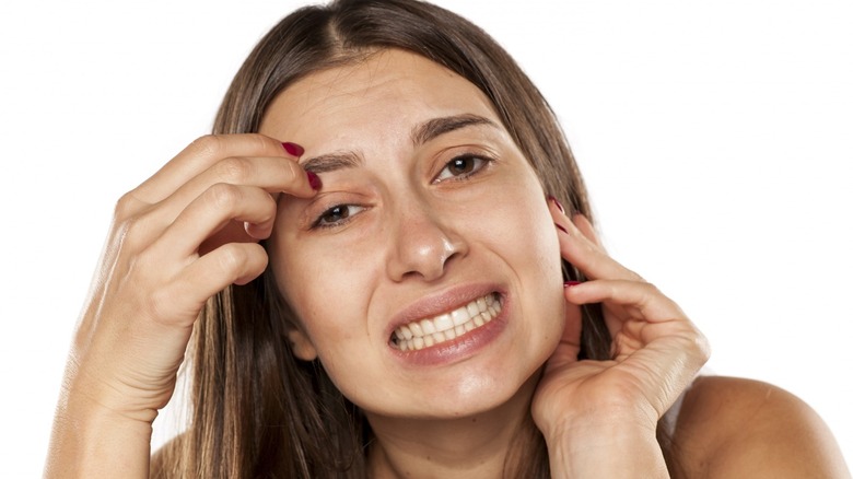 woman scratching eyebrow