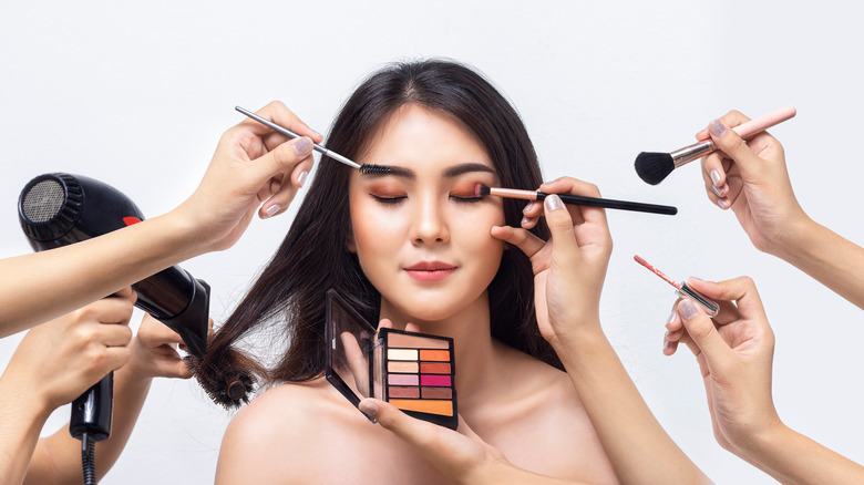 Woman gets her makeup done by four sets of hands