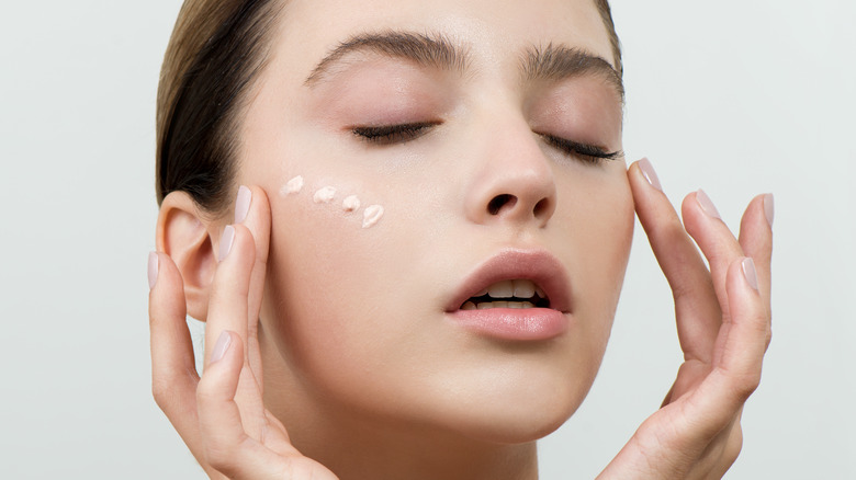 Woman applying concealer to dark spots